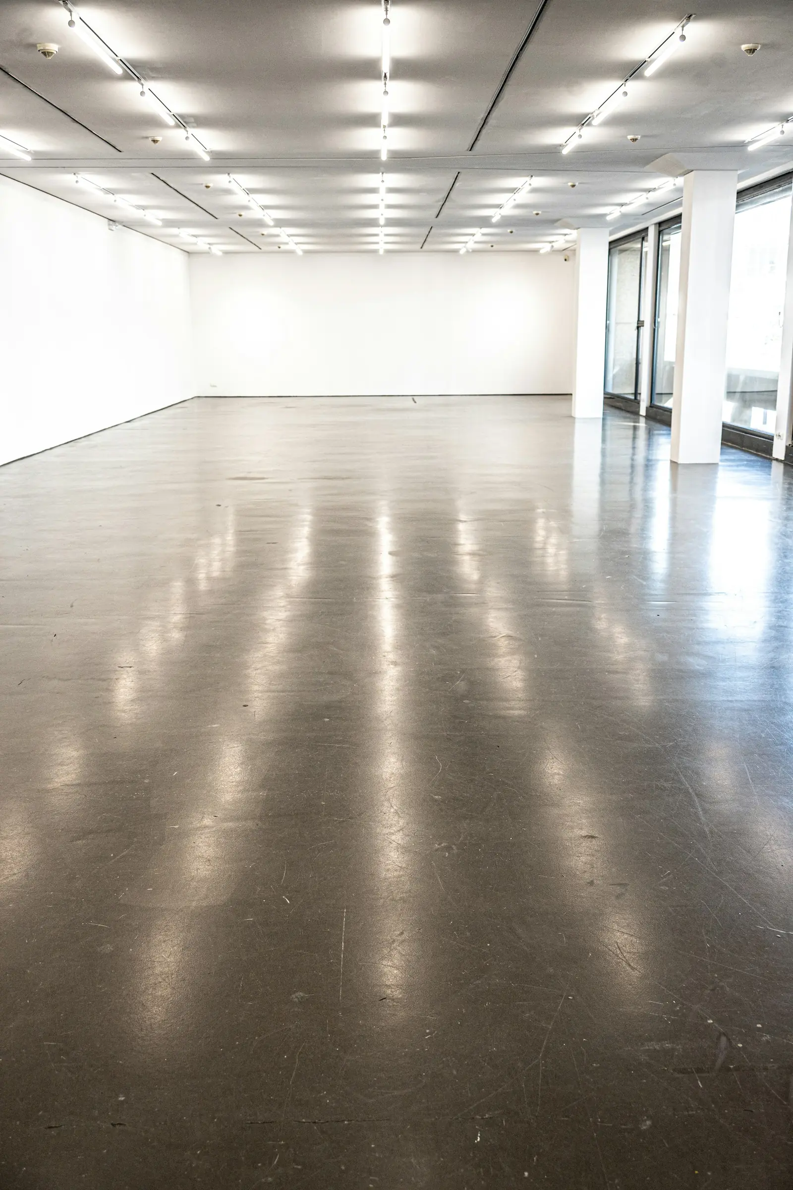 Gallery with a glossy polished concrete floor reflecting the lights